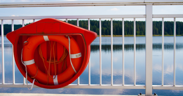 closeup-shot-red-lifebuoy-hanged-white-railing-bridge